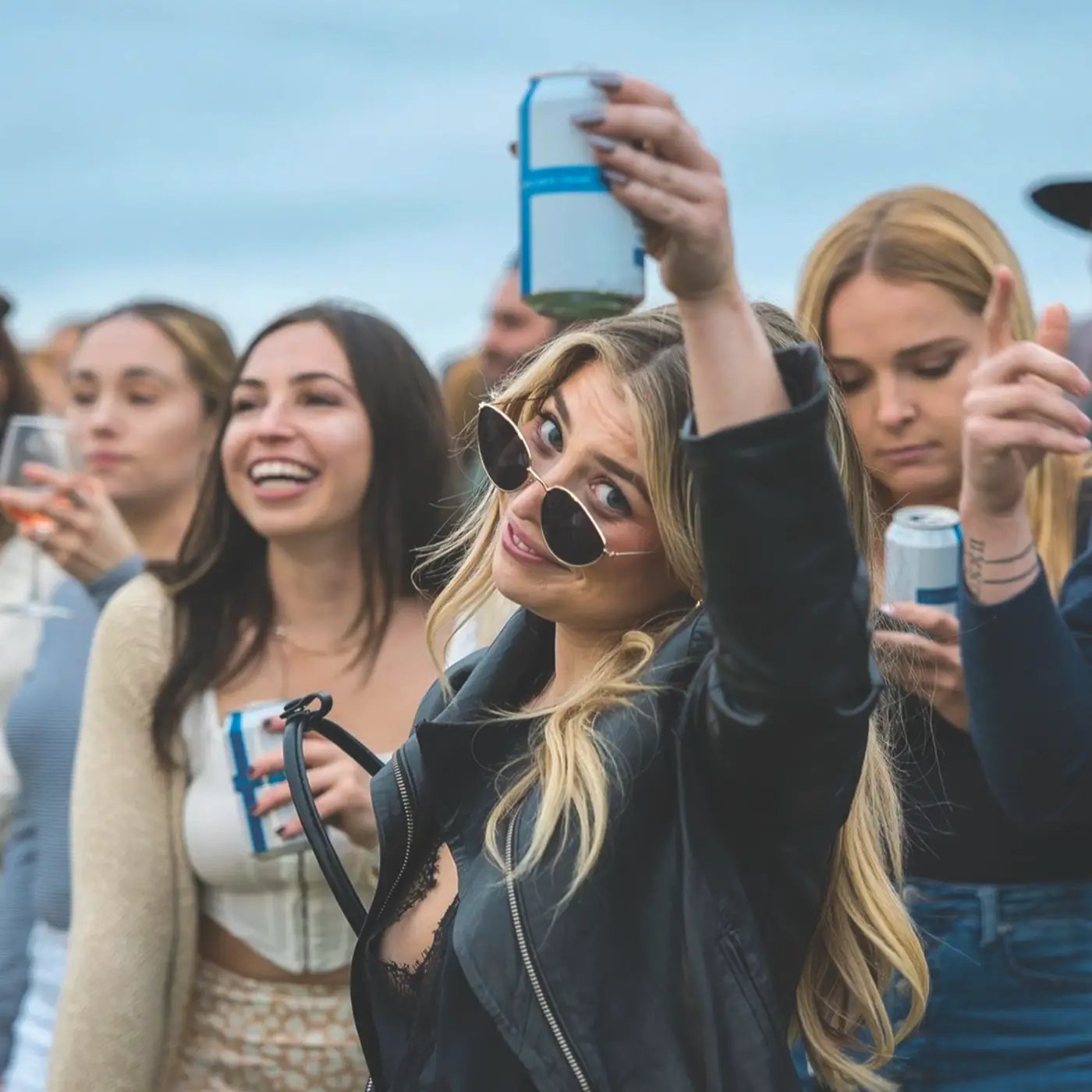 Woman raising a can of Loncaro surrounded by friends