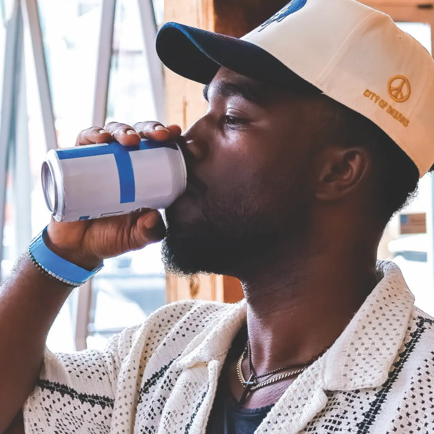 Man in a baseball cap drinking a can of Loncaro